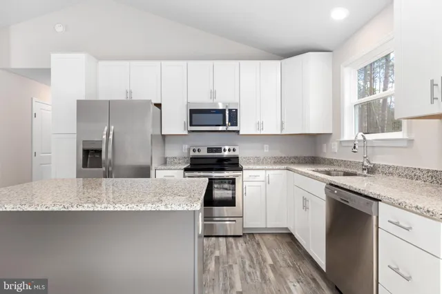 a kitchen with granite countertop a refrigerator sink and microwave