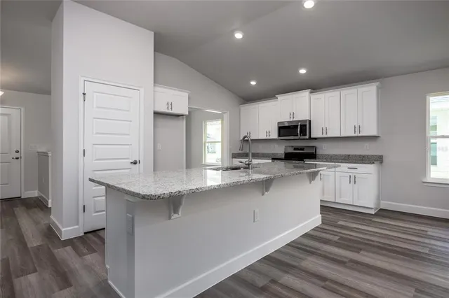 a view of kitchen with granite countertop white cabinets and stainless steel appliances