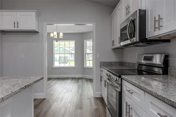 a view of an empty room with wooden floor and window