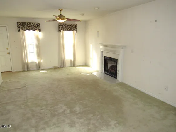 an empty room with a fireplace and windows