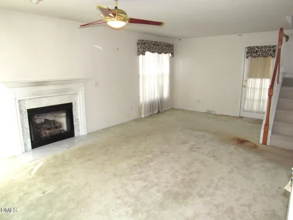 an empty room with windows and fireplace