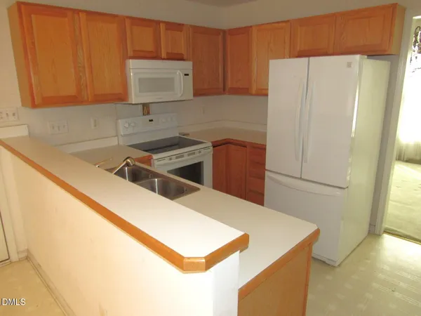a kitchen with stainless steel appliances a refrigerator a sink a stove and white cabinets