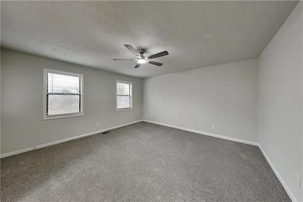 an empty room with windows and ceiling fan