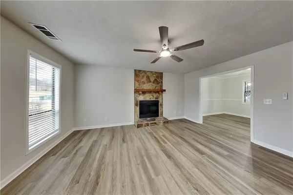 a view of an empty room with a window and wooden floor