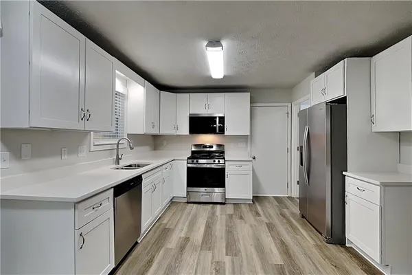 a kitchen with granite countertop a sink stove and refrigerator