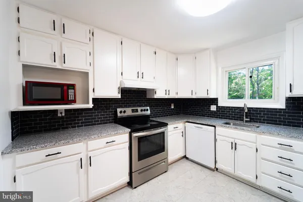 a kitchen with white cabinets and refrigerator