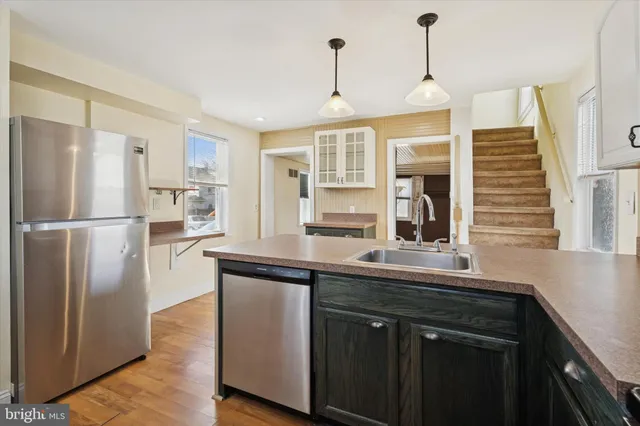 a kitchen with stainless steel appliances granite countertop a refrigerator a sink dishwasher a stove and white cabinets with wooden floor