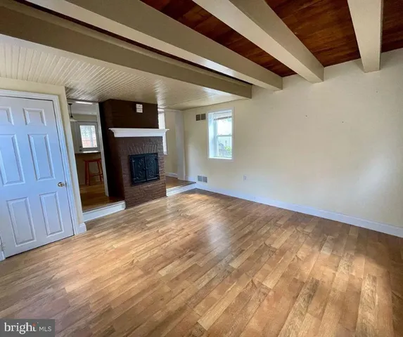 a view of empty room with wooden floor and fireplace