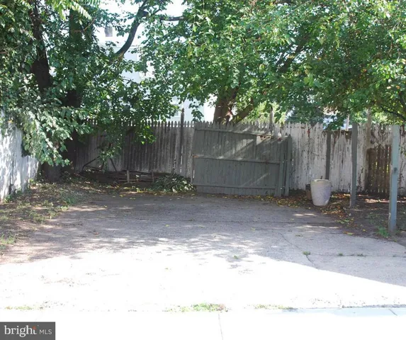 a backyard of a house with large trees and a wooden fence