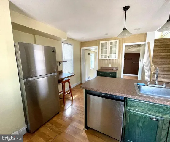 a kitchen with kitchen island wooden floor and refrigerator