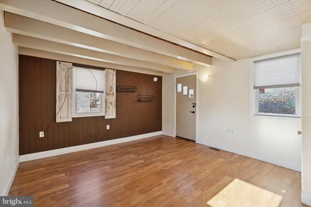 a view of an empty room with wooden floor and a window