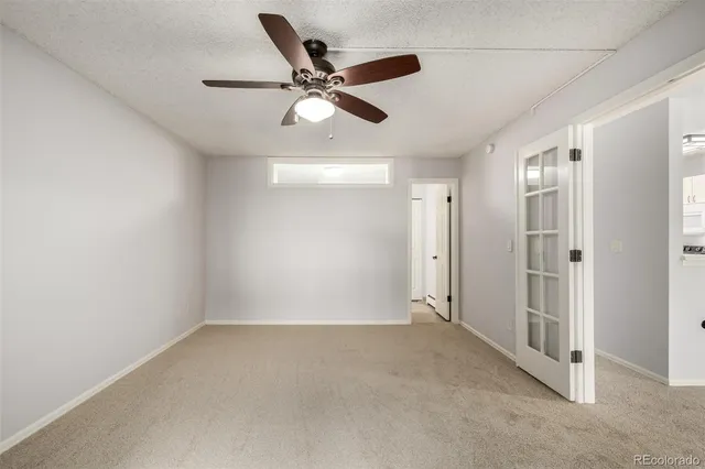 an empty room with windows and ceiling fan