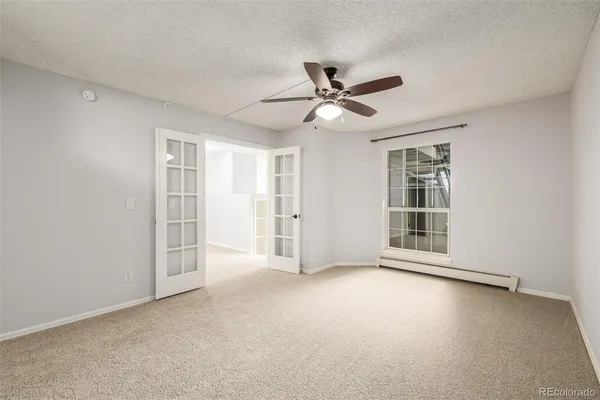 an empty room with windows and ceiling fan