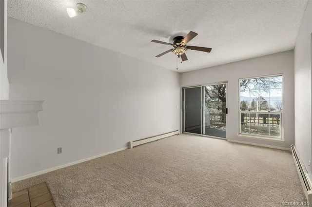 an empty room with fireplace and ceiling fan