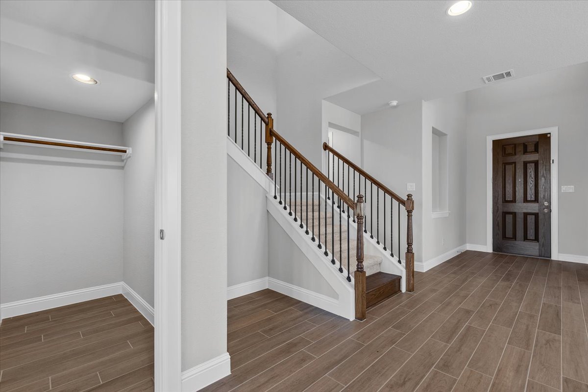 A welcoming entryway with rich wood-look flooring and a prominent staircase leads to upper levels.