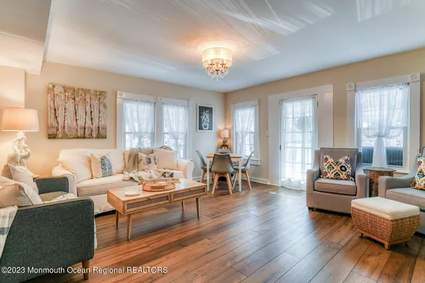 a living room with furniture a chandelier a large window and a dining table