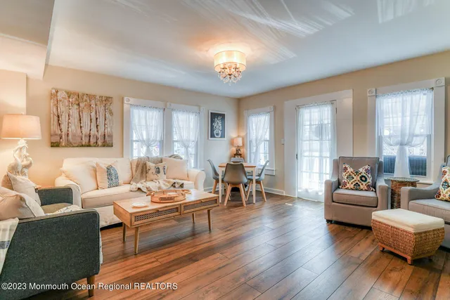 a living room with furniture a chandelier a large window and a dining table