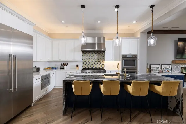 a kitchen with stainless steel appliances granite countertop a stove a kitchen island a dining table and chairs with wooden floor