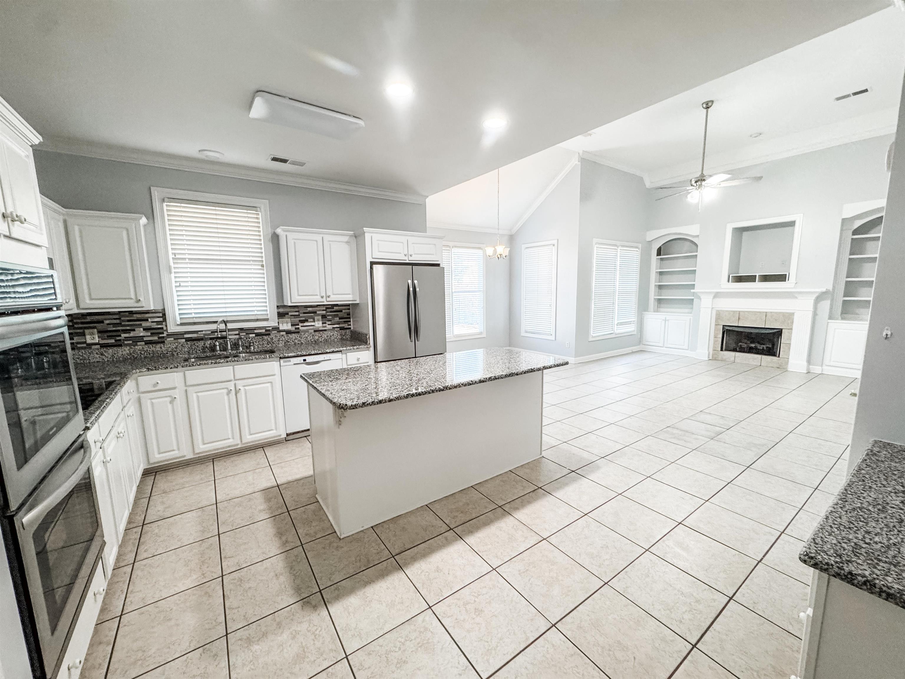 472 Hunters Mill Cove Collierville, TN 38017 - Photo 3 of 15 a large white kitchen with granite countertop a stove a sink dishwasher and white cabinets with wooden floor