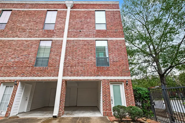 a view of a brick house with large windows and a large tree