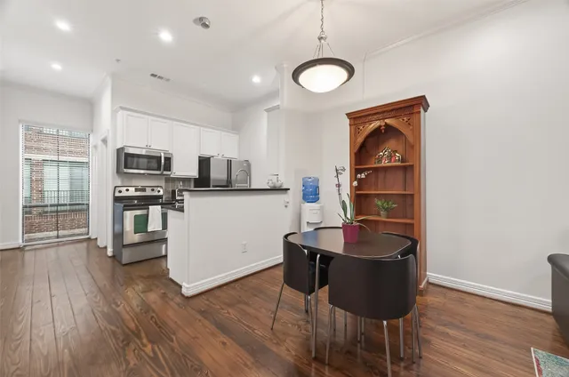 a kitchen with stainless steel appliances granite countertop a stove top oven a sink a dining table and chairs with wooden floor