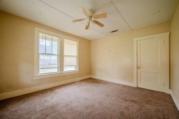 an empty room with fan and windows