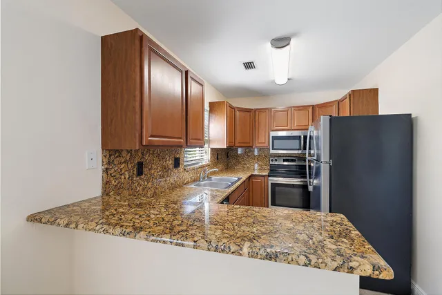 a kitchen with stainless steel appliances granite countertop a refrigerator a stove and a sink with granite countertops