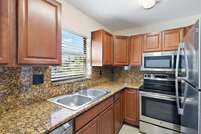 a kitchen with granite countertop stainless steel appliances a sink stove and cabinets