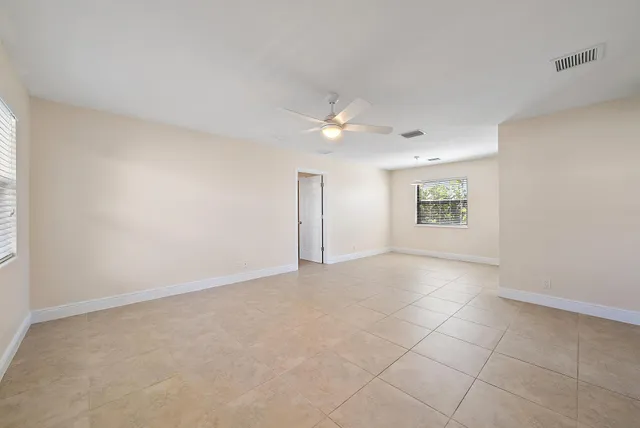 an empty room with a ceiling fan and window