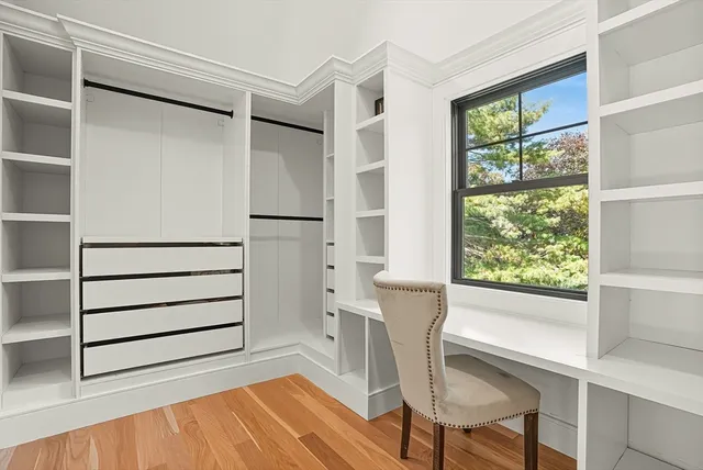 a view of walk in closet with wooden floor and chair
