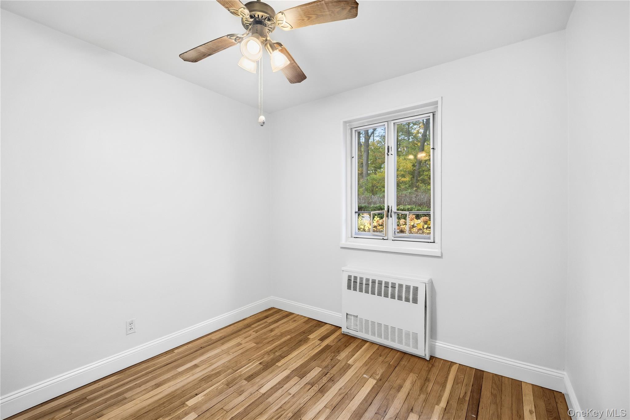 228-08 Stronghurst Avenue, Unit LOWR Queens, NY 11427 - Photo 12 of 20 a view of an empty room with wooden floor and a window