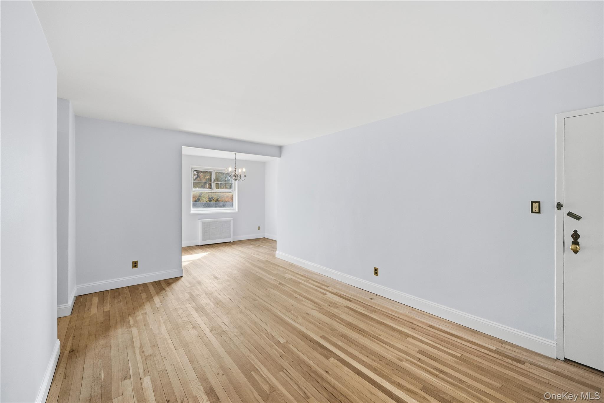 228-08 Stronghurst Avenue, Unit LOWR Queens, NY 11427 - Photo 5 of 20 an empty room with wooden floor and windows