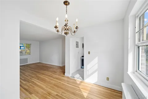 a view of an empty room with window and wooden floor