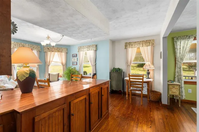 a kitchen with stainless steel appliances granite countertop a refrigerator a stove top oven a chimney and wooden floor