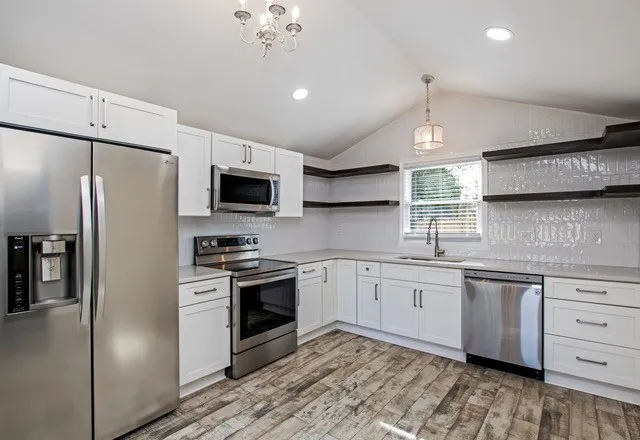 a kitchen with stainless steel appliances granite countertop a refrigerator a stove a sink and a microwave