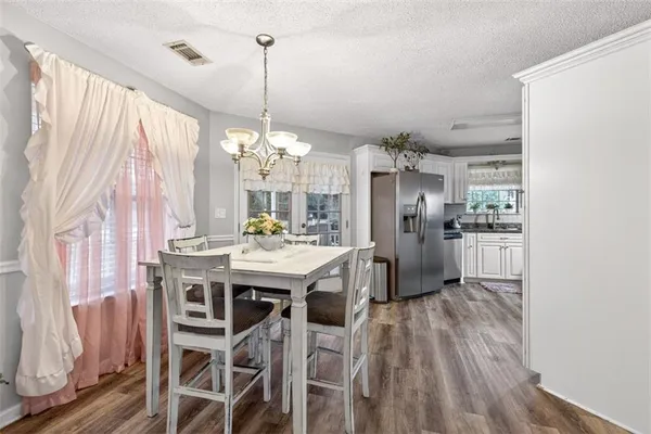 a kitchen with stainless steel appliances granite countertop a refrigerator a sink dishwasher a stove and white cabinets with wooden floor