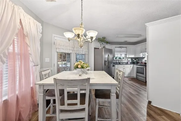 a kitchen with stainless steel appliances granite countertop a refrigerator a sink dishwasher a stove and white countertops with wooden floor