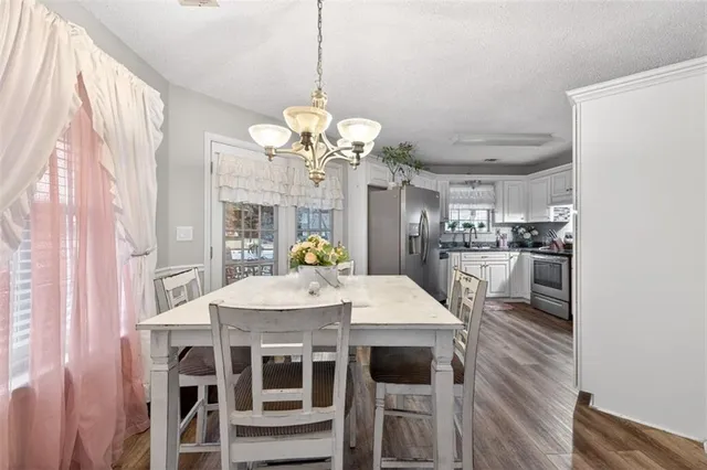 a kitchen with stainless steel appliances granite countertop a refrigerator a sink dishwasher a stove and white countertops with wooden floor