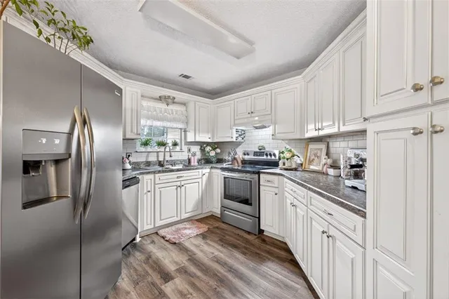 a kitchen with granite countertop white cabinets and white appliances