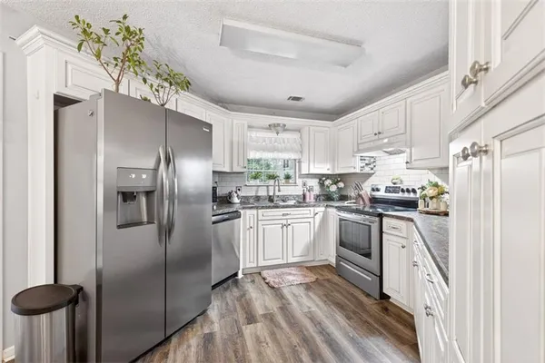 a kitchen with granite countertop white cabinets and stainless steel appliances