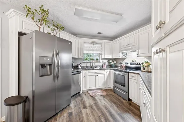 a kitchen with granite countertop white cabinets and stainless steel appliances