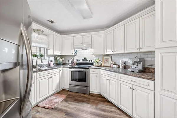 a kitchen with granite countertop a sink stove a window and cabinets