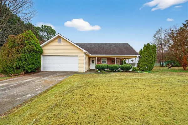 a front view of house with yard and trees in the background