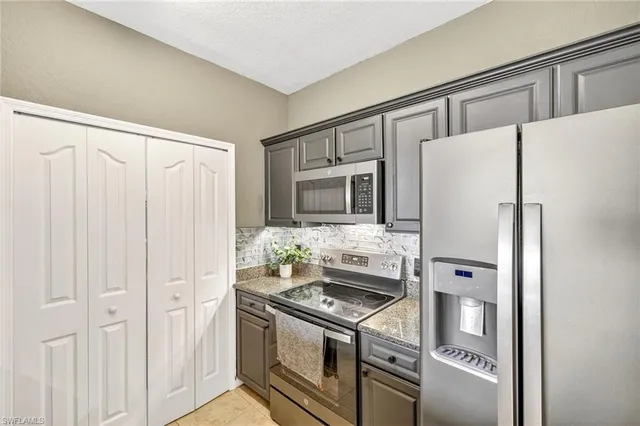 a kitchen with stainless steel appliances kitchen island granite countertop a refrigerator and a stove top oven