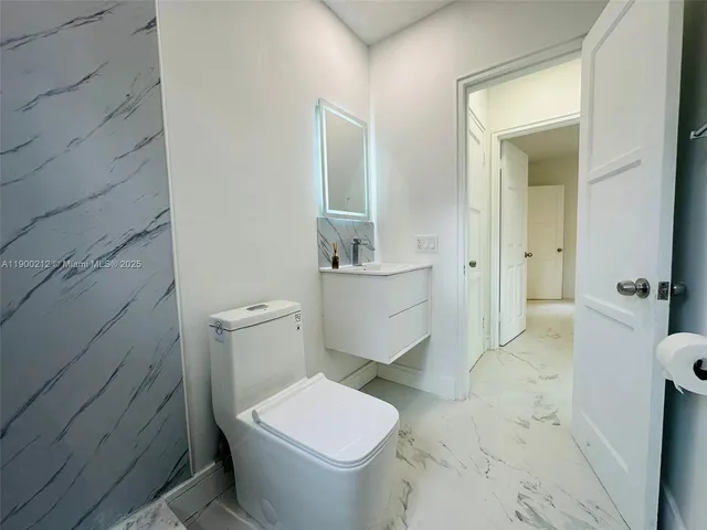 a white toilet sitting next to a bathroom sink and a mirror