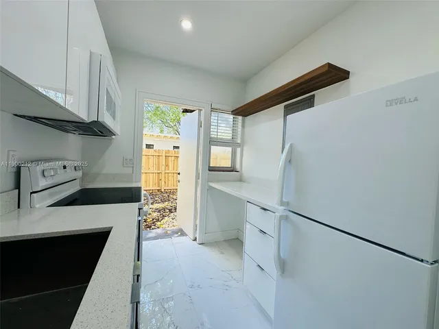 a kitchen with white cabinets and a refrigerator