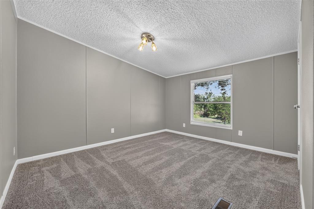 449 Big Salty Lane Springtown, TX 76082 - Photo 22 of 25 Interior room featuring gray panel walls, textured ceiling, and gray patterned carpeting