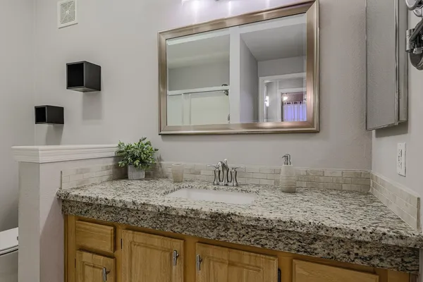 a bathroom with a granite countertop sink and a mirror
