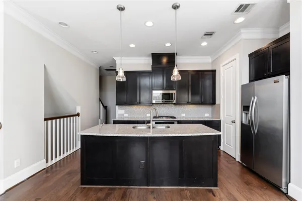 a kitchen with stainless steel appliances kitchen island granite countertop a stove and a refrigerator
