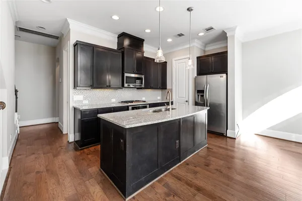 a kitchen with a sink chandelier and wooden floor